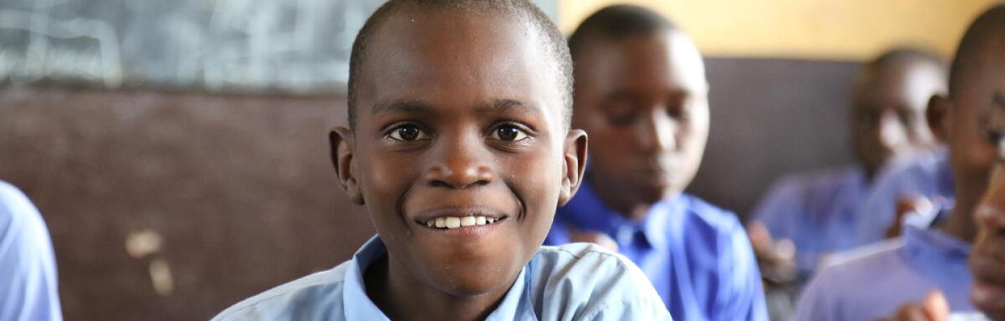 A cheerful boy enjoying a meal in a classroom.
