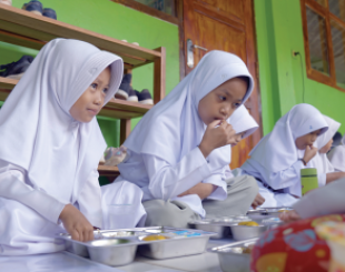  Children sitting on floor, eating together.
