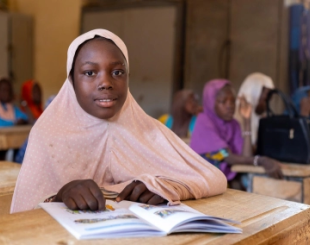 A student sits attentively at a desk in a classroom.