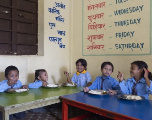  some children from Nepal share a meal cooked for them in school