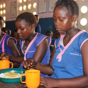 Three girls having their meals at school.